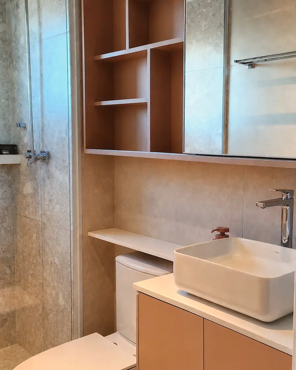 Banheiro planejado com nichos amadeirados, bancada clara e cuba branca assinado pela CAPI Design